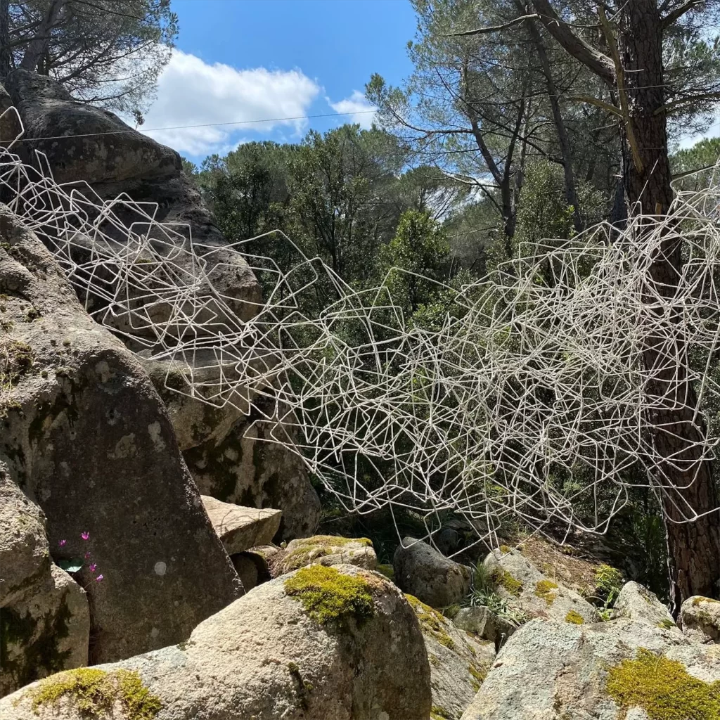 installazione composta da fili metallici che si sovrappongono e intrecciano formando una specie di ragnatela, risospesi tra delle rocce in granito